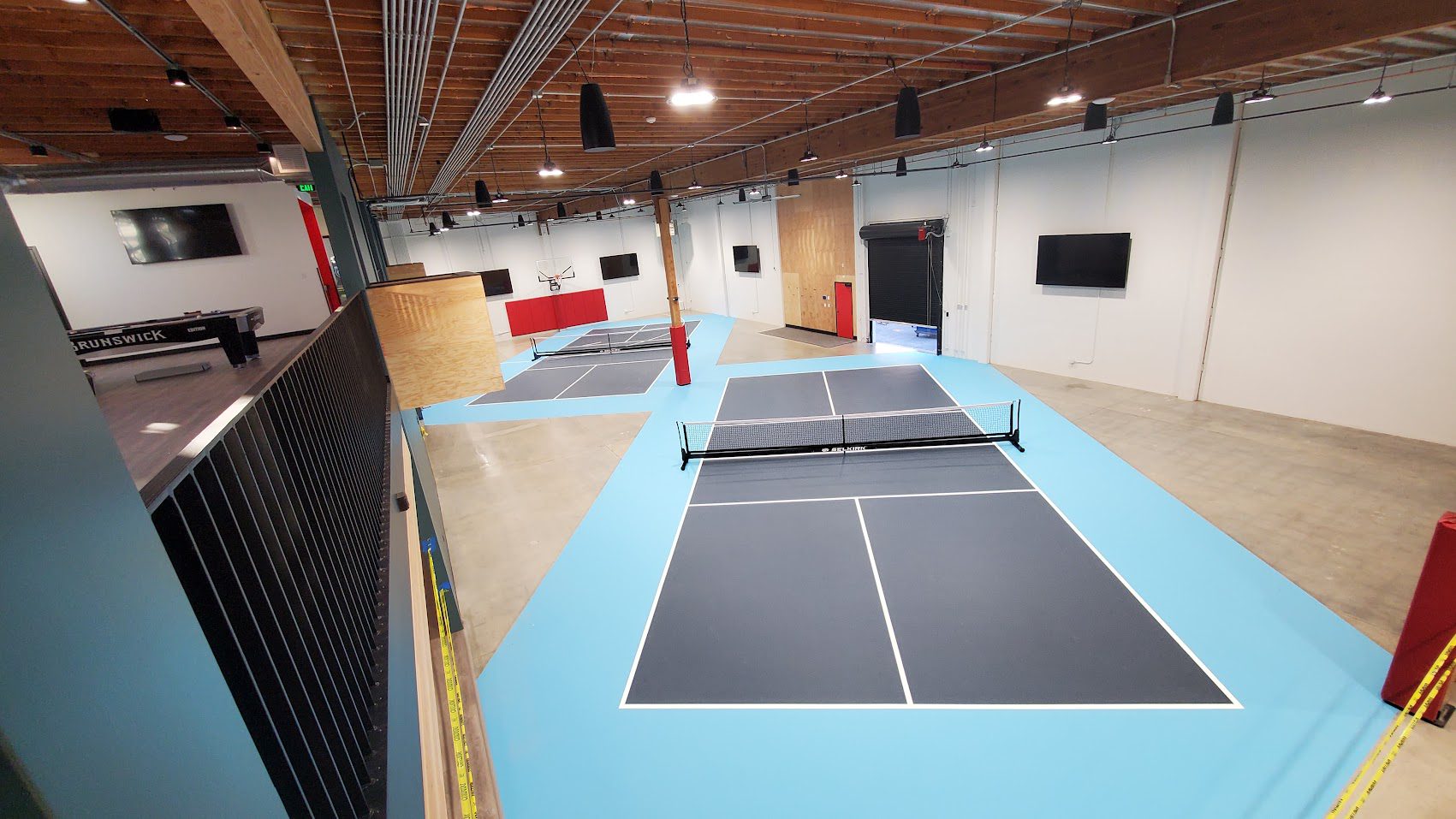 Indoor sports facility with ping pong tables and gym equipment.