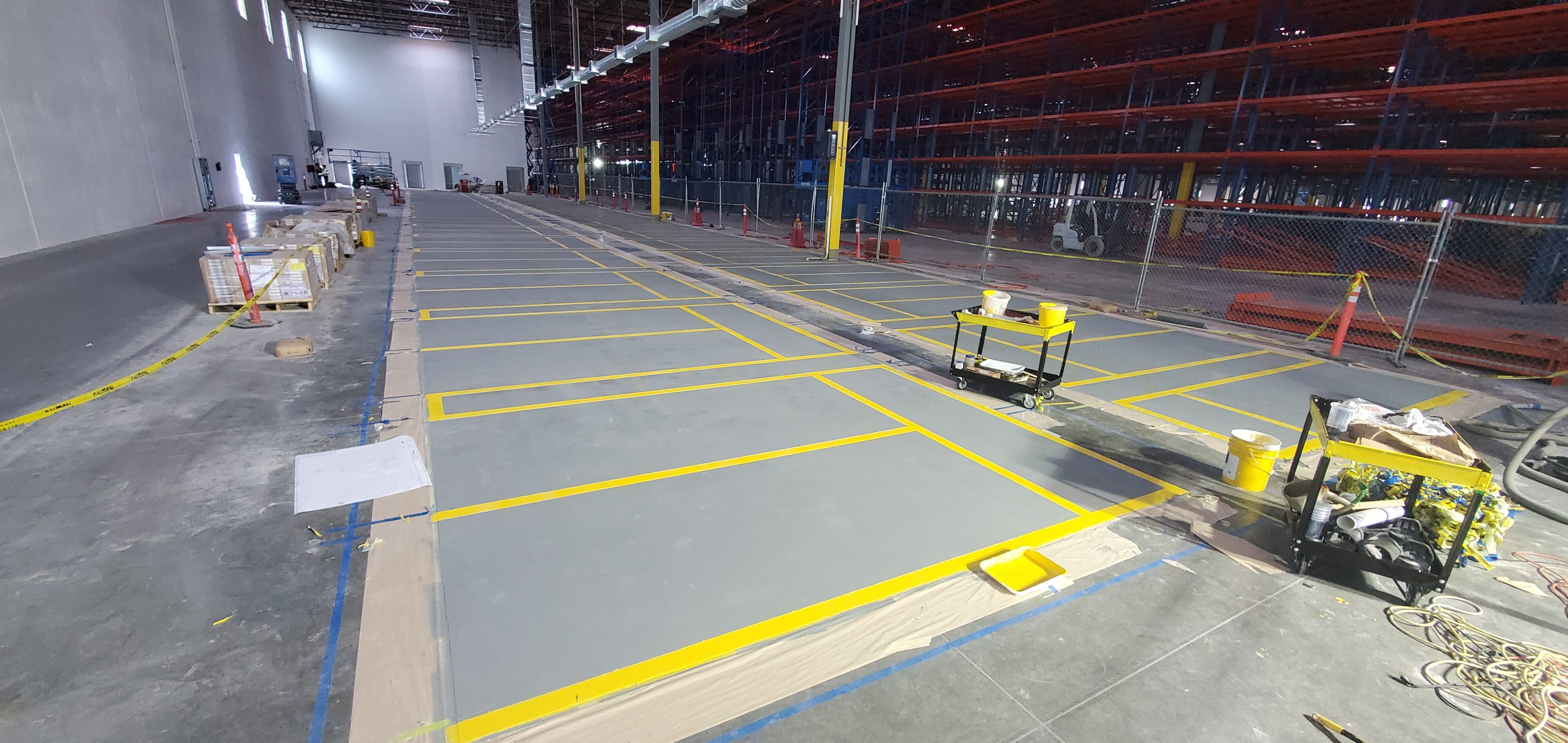 A clean, organized industrial floor with marked yellow lines and safety barriers.