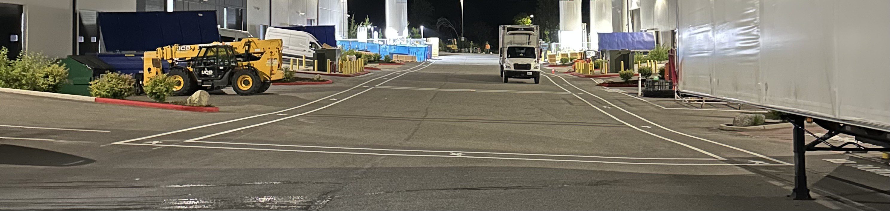 Airport runway with ground vehicle at night under bright lights.