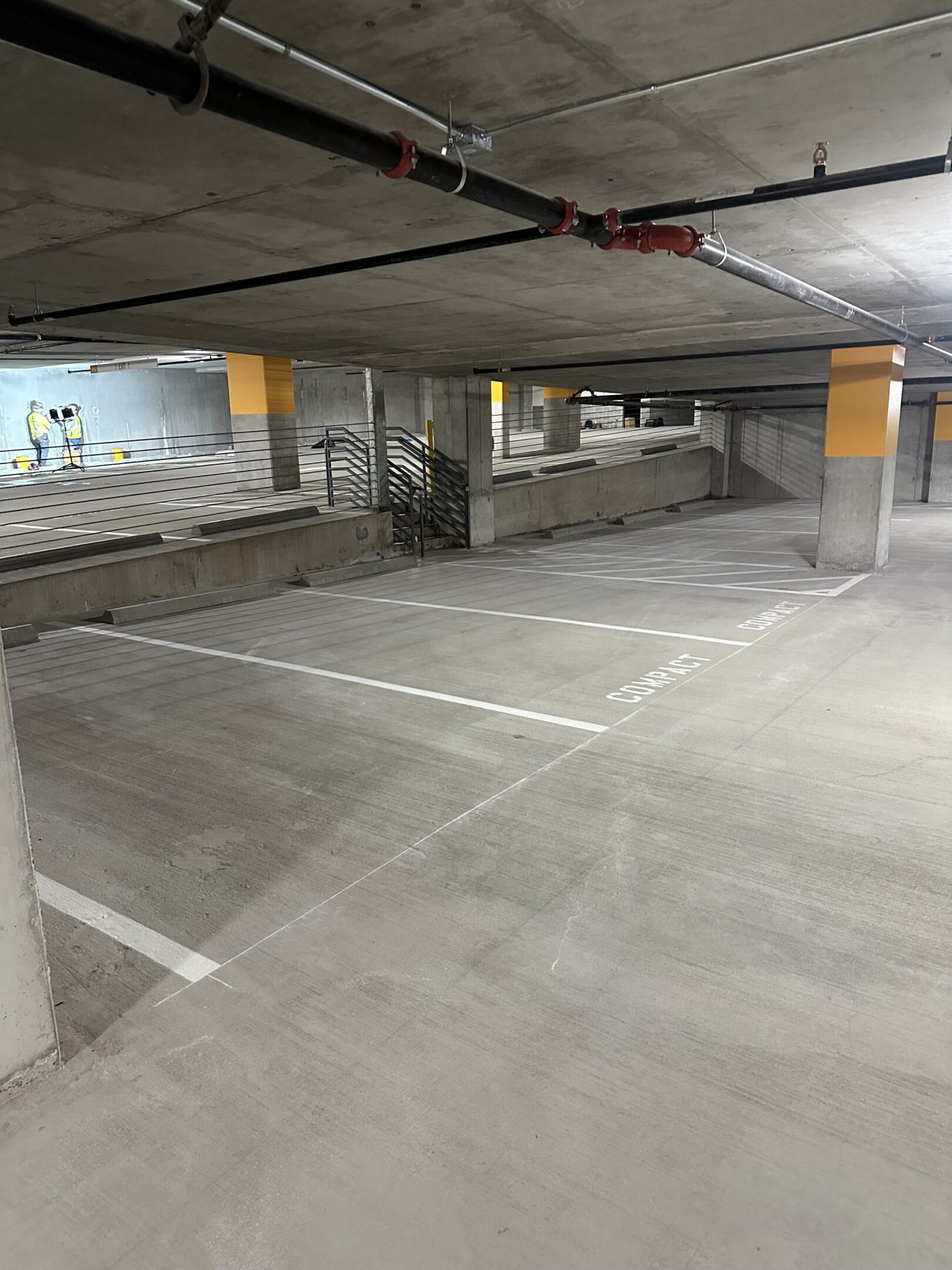 Empty indoor parking garage with concrete floors and columns.