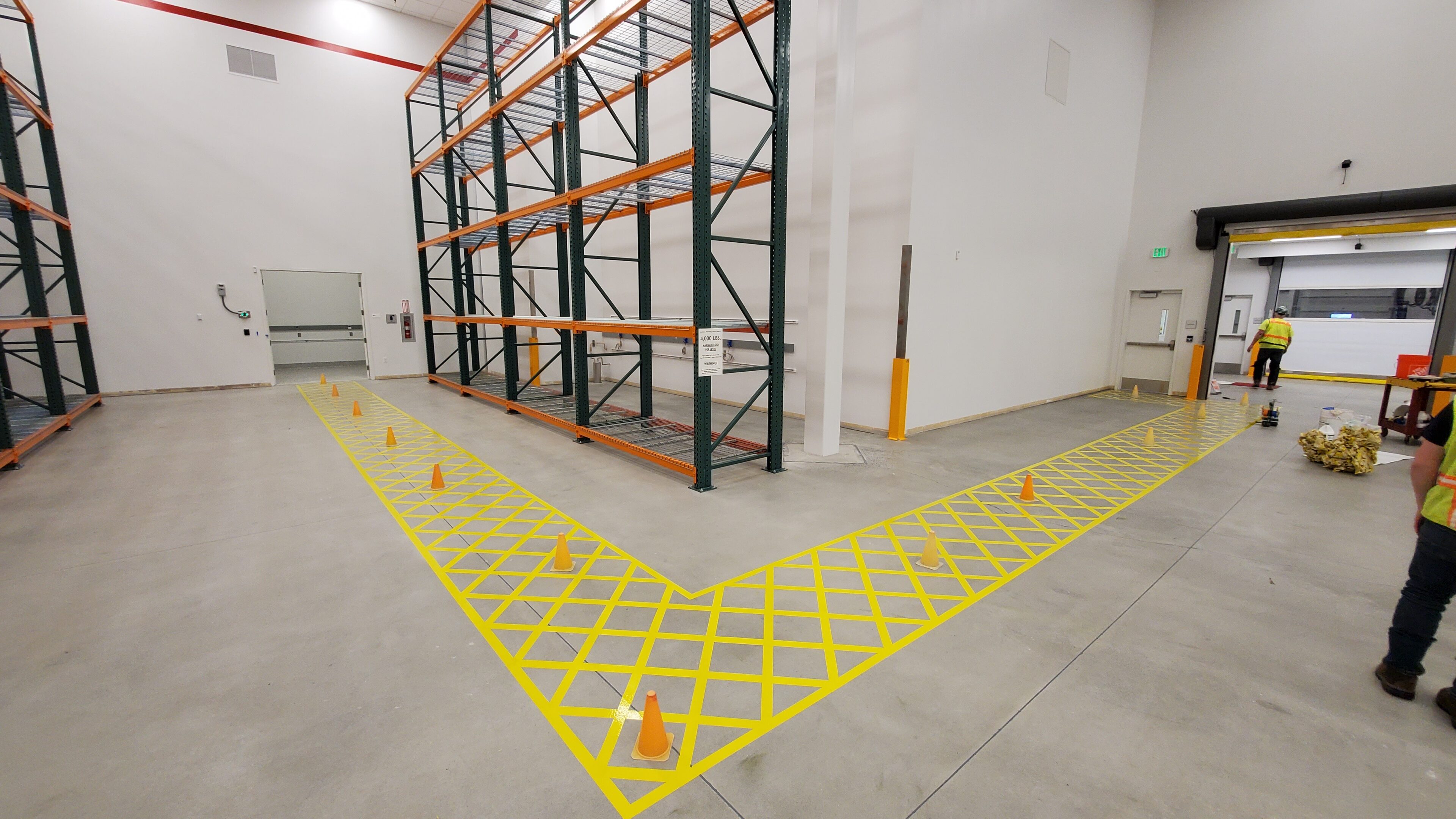 Empty warehouse shelving with yellow safety markings on the floor.